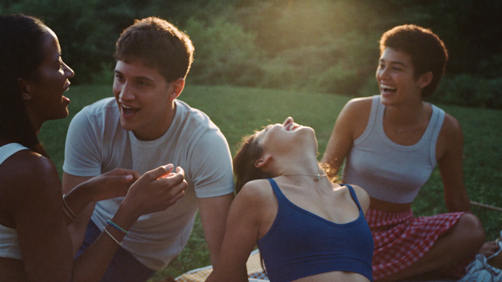 Friends laughing together at a golden-hour picnic