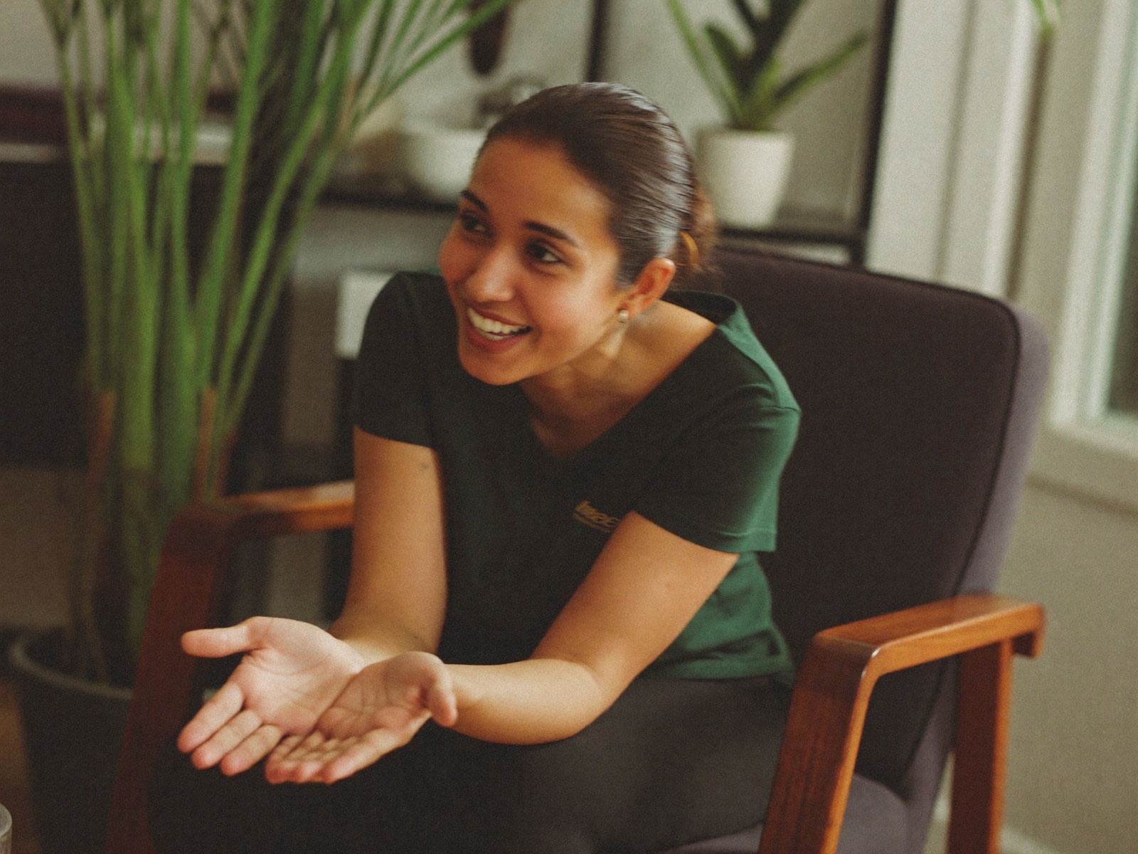 A warm, welcoming therapist in a bright, plant-filled office